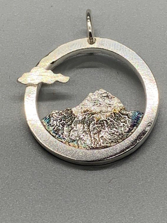 Round pendant with a textured outline of Mount Shasta, oxidized, with a small cloud on the rim.