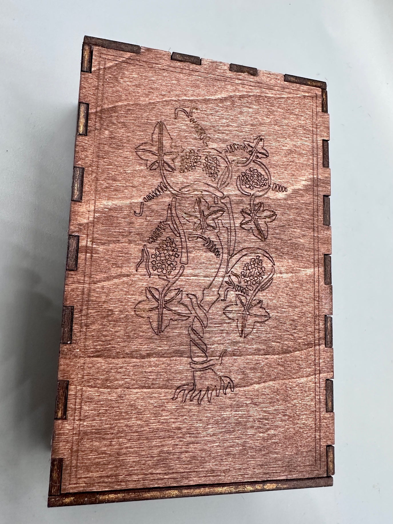 Top view of closed box, showing the vines, leaves and grapes engraving.