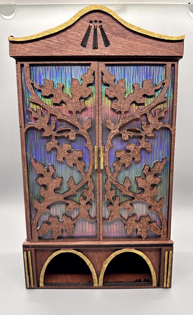 Wood wardrobe with oak leaf pattern on the doors and an Awen symbol at the top.