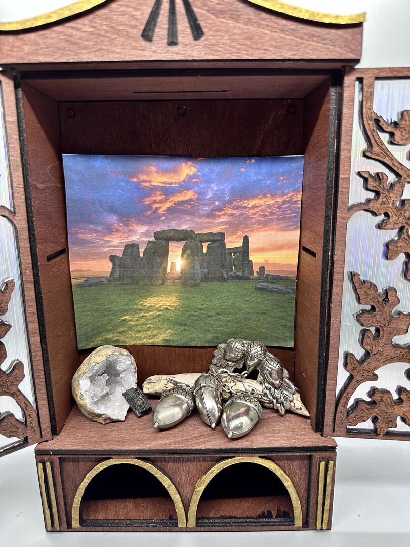 Decorating idea for the Altar with a photo of Stonehenge, a geode, a rock shard, a small piece of driftwood and silver acorns.