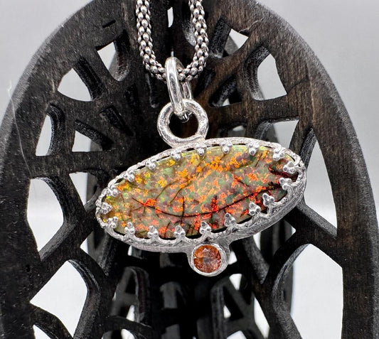 Bright orange and red sparkles in a tiny opal accented with a canary stone.