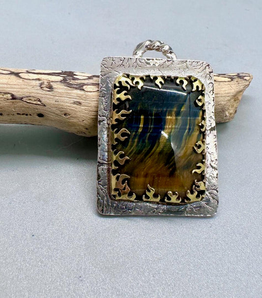 Square silver pendant with brass flames holding a rectangular tiger iron stone.