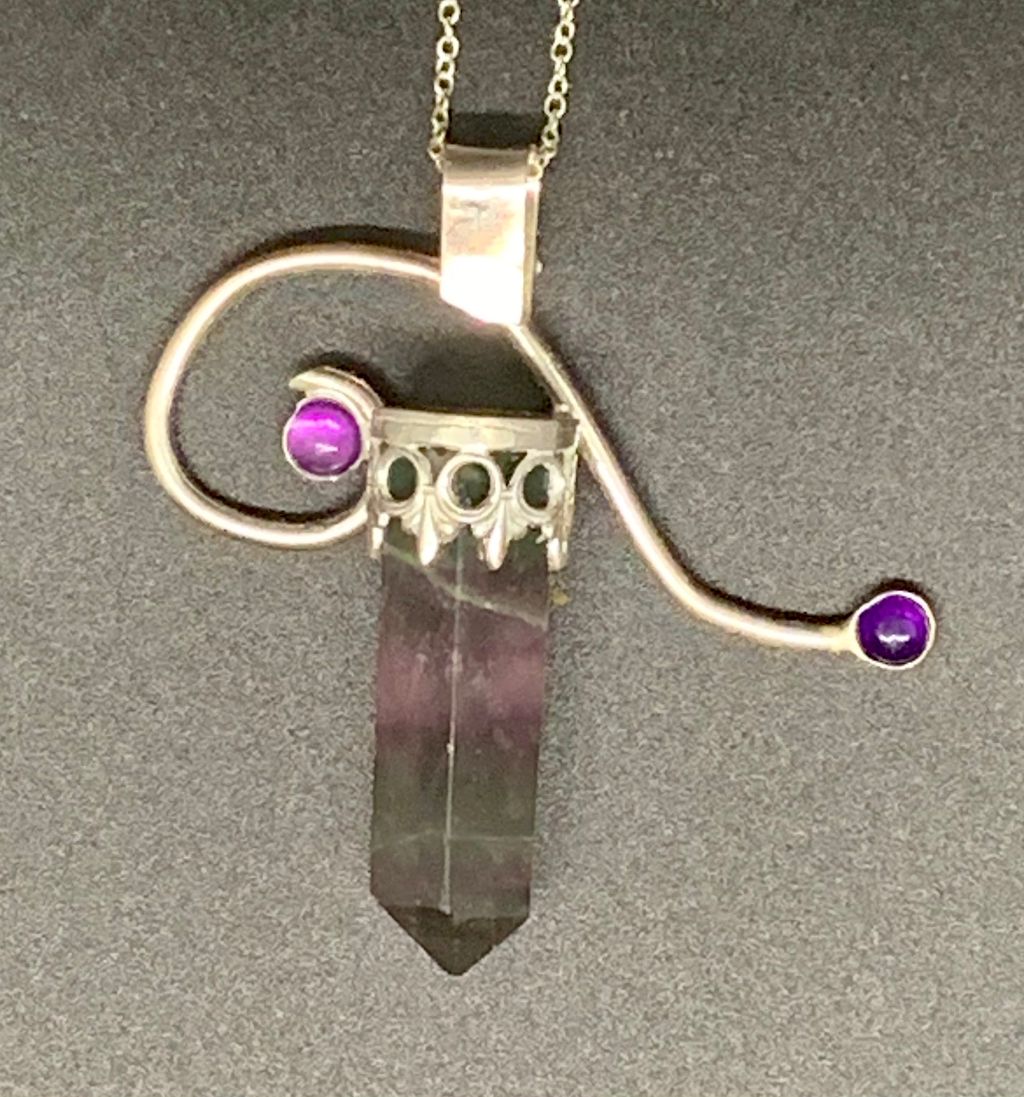 Tourmaline with a bezel base and a freeform silver shape with two purple stones.