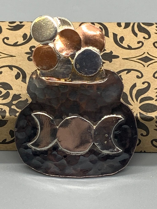 Hammered copper pin in the shape of a cauldron with the triple moon symbol and bubbles of copper and silver