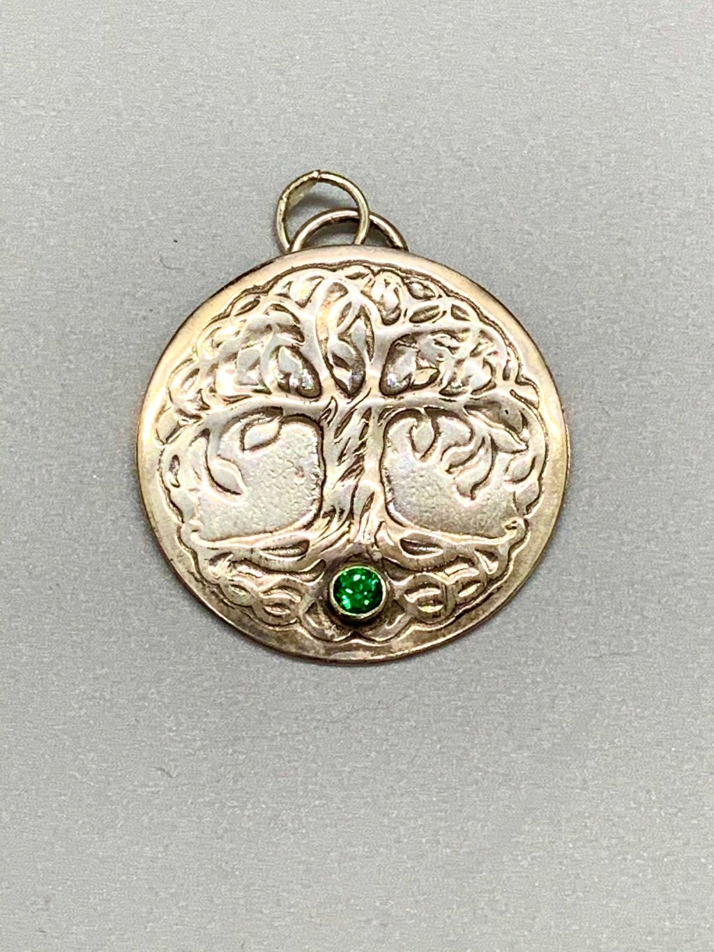 Round silver pendant embossed with the Tree of Life and a tube set green stone.