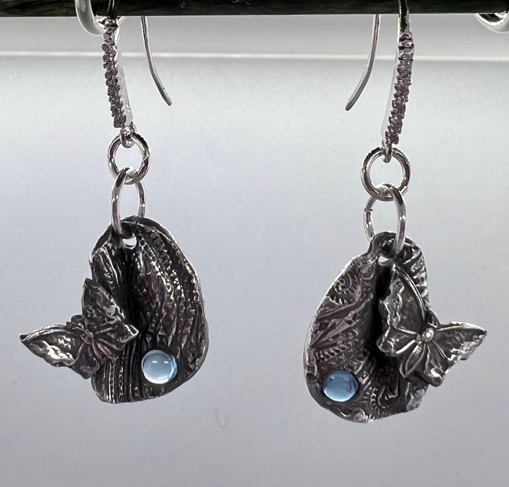 Textured and folded ovals with a blue stone and a butterfly on each.