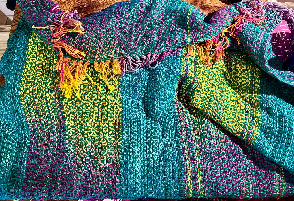 Handwoven cotton cloth in purples, blues, and yellow with a green weft.