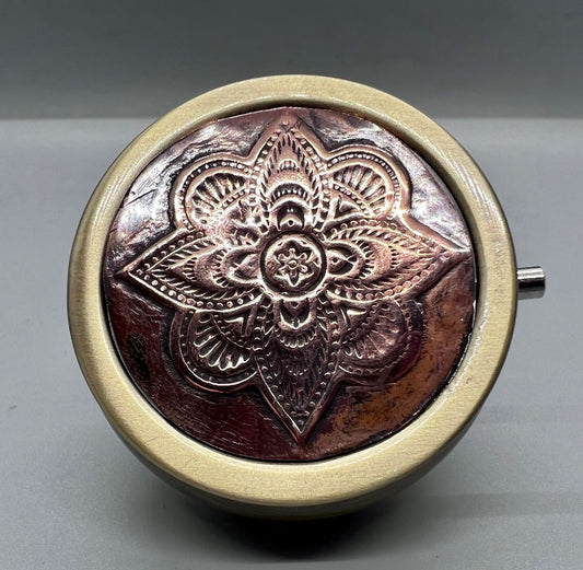 Pushbutton fliptop round case with a mandala embossed round copper highlight.