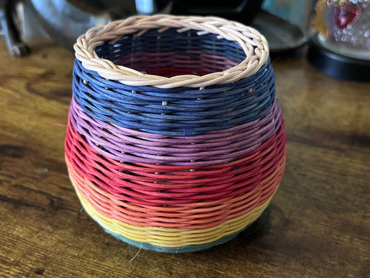 Small handwoven reed basket in rainbow colors.