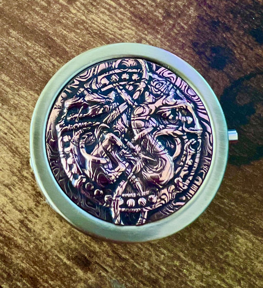 Round pushbutton fliptop pill case with a round copper decoration of a two heded celtic dragon.