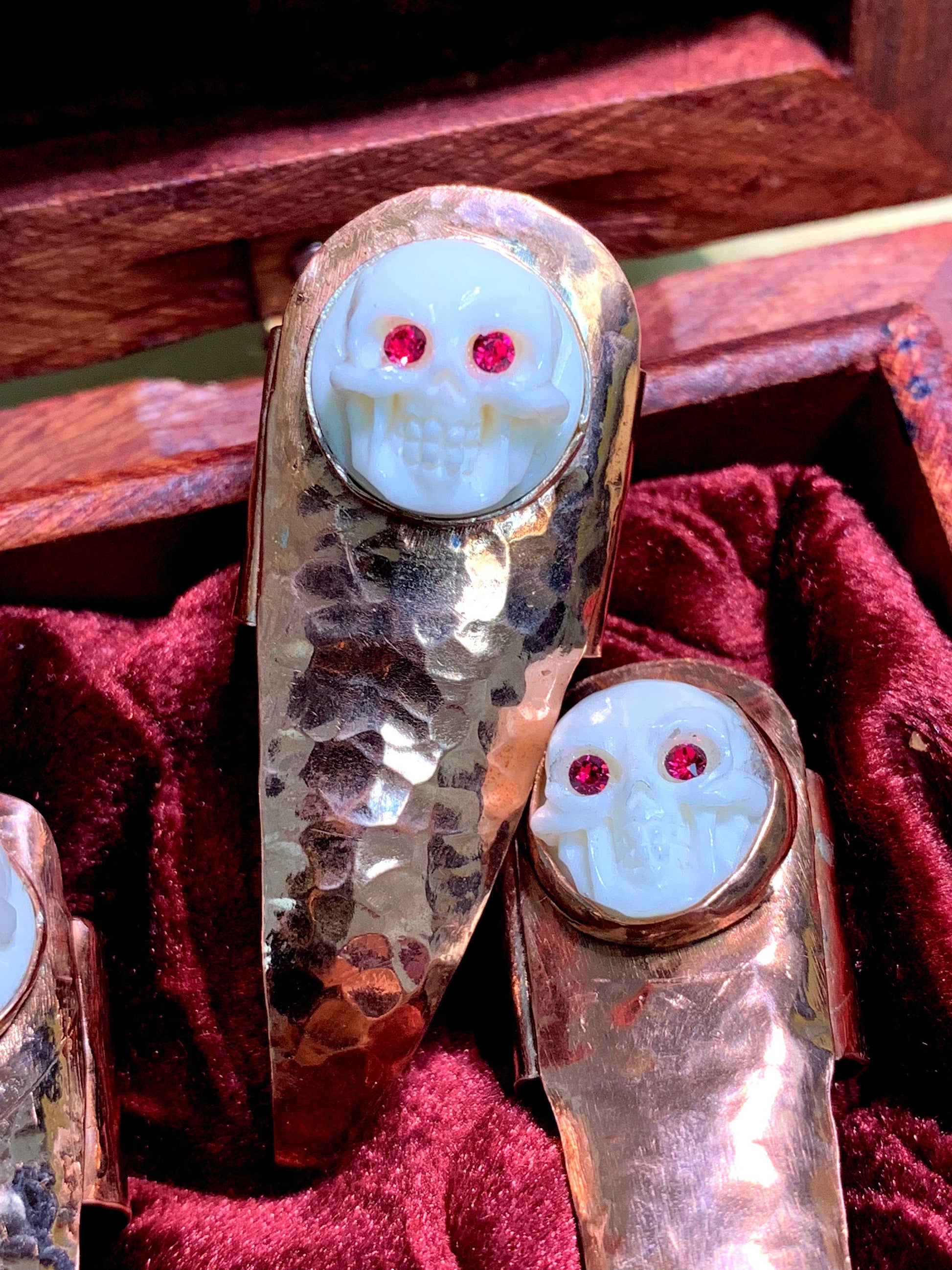 Hammered copper claws with bone skulls inset with red crystals, set of five.