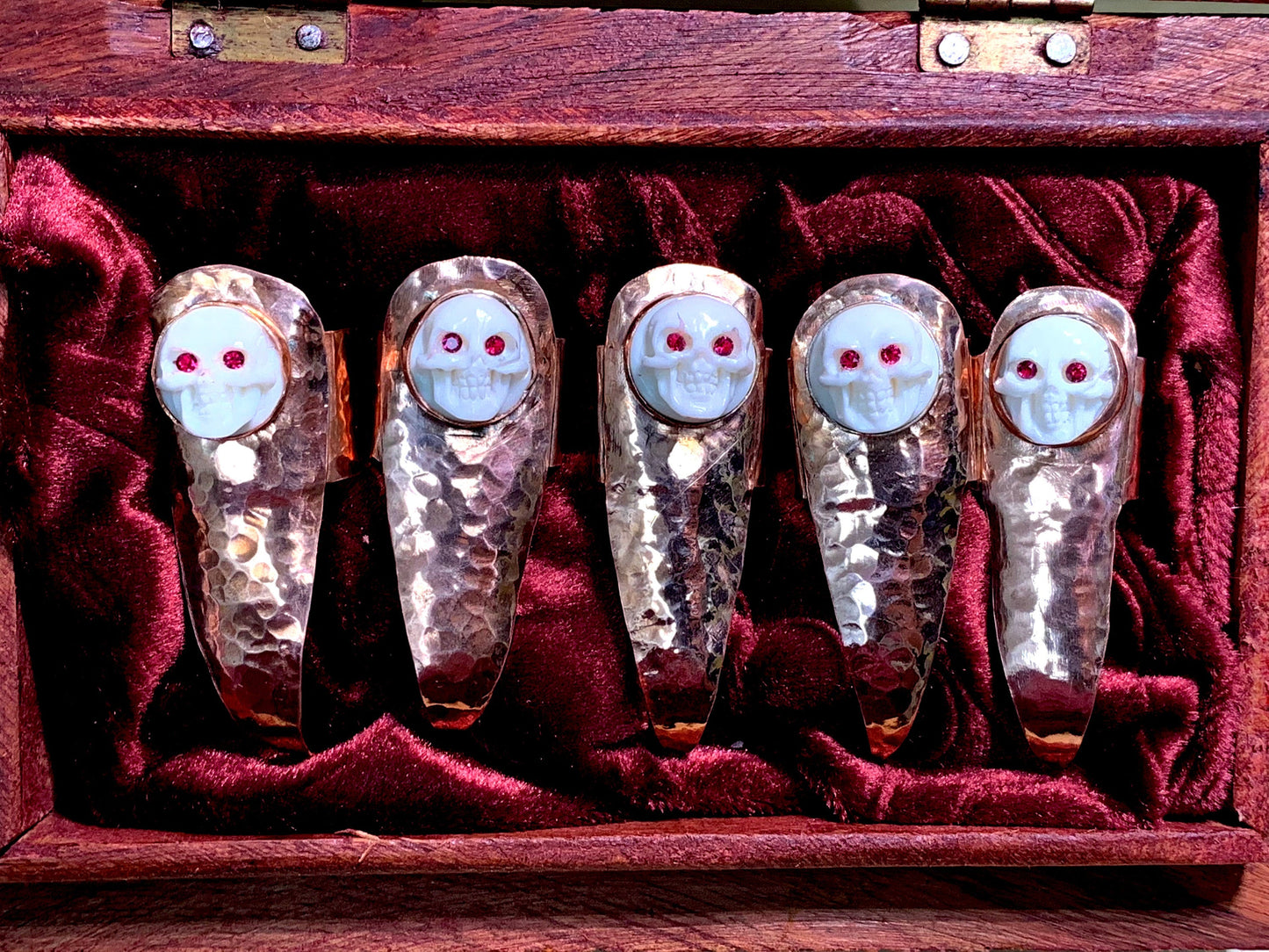 Hammered copper claws with bone skulls inset with red crystals, set of five.