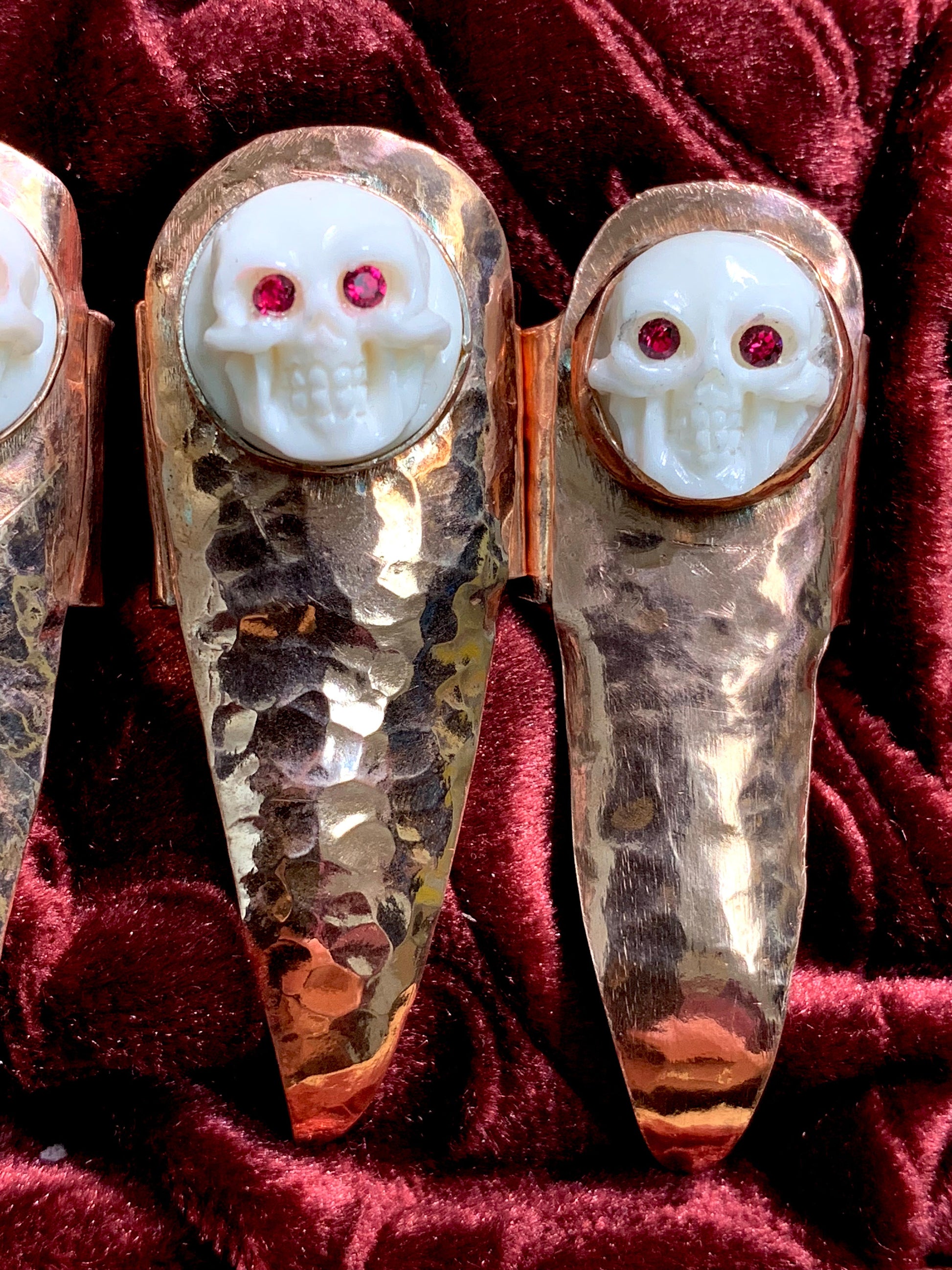 Hammered copper claws with bone skulls inset with red crystals, set of five.