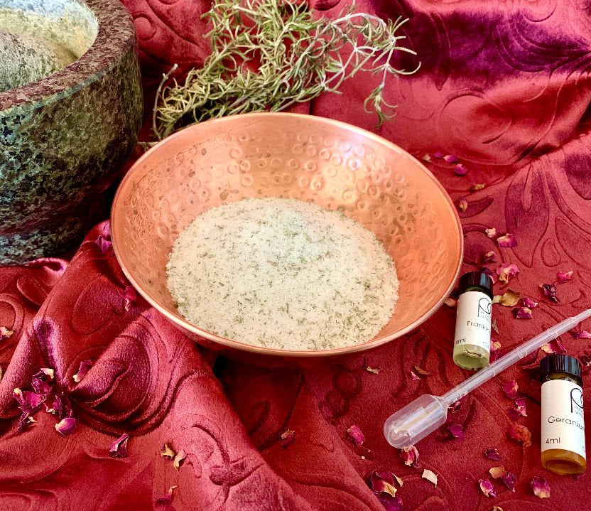 Stock photo of copper bowl with salt, dried rosemary, and oils of Frankincense and Geranium.