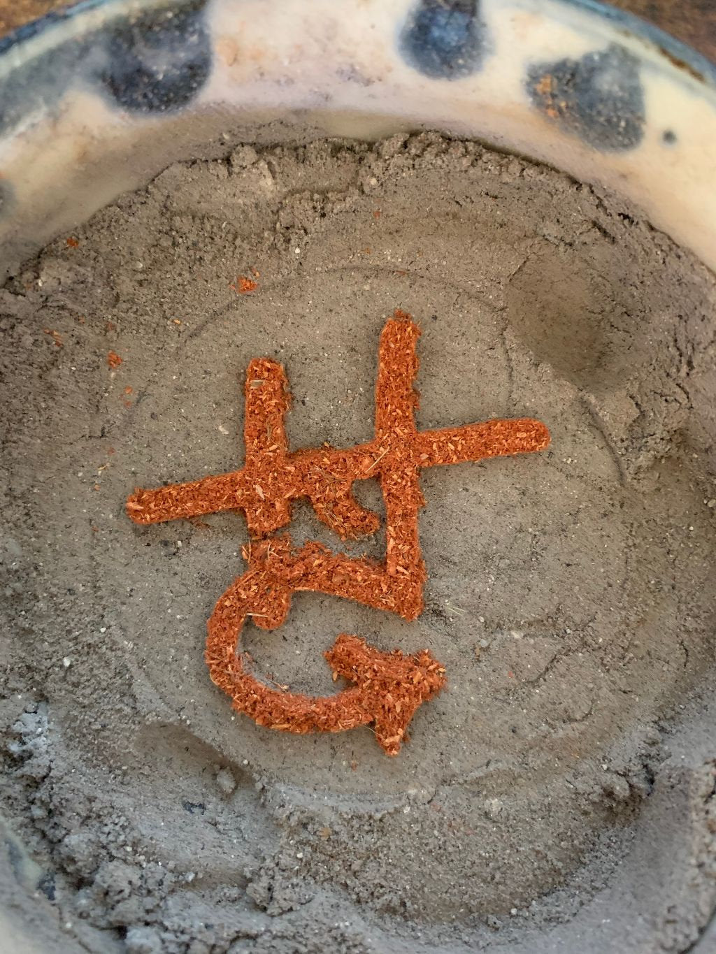 Incense trail on ash, in shape of logo